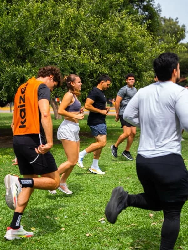 Grupo corriendo en un parque, con el peto naranja de Kaizer en primer plano